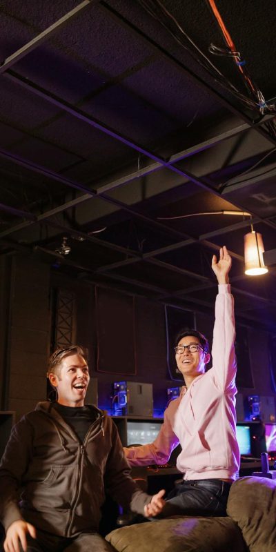 A group of friends celebrate a victory in a vibrant gaming lounge, embracing teamwork and technology.