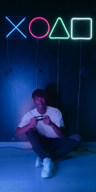 A young man immersed in gaming under vibrant neon lights, playing on a game console.