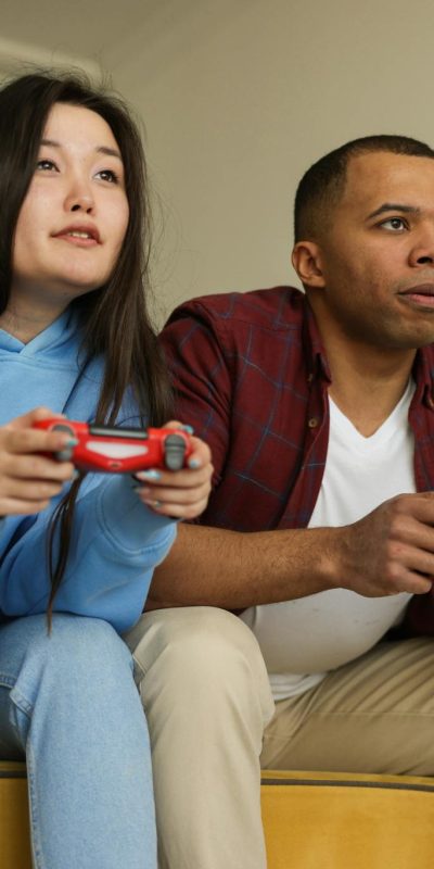 Interracial couple intense in a gaming session, sitting together indoors with wireless controllers.