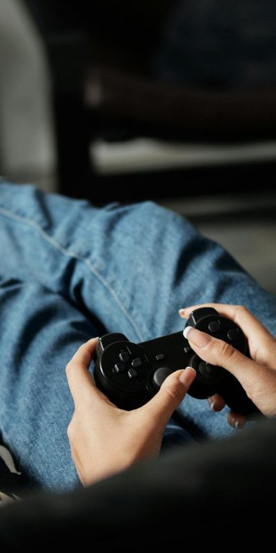 Person in denim jeans relaxing and playing video games indoors.